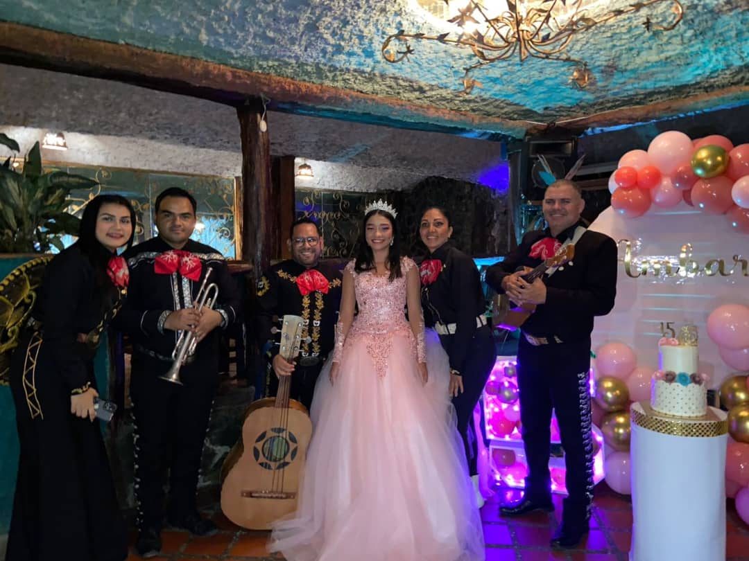 Mariachi en unos quince años, junto a la quinceañera y su torta